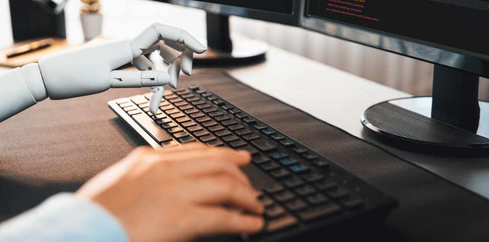 Human right hand and robot left hand typing on a computer keyboard